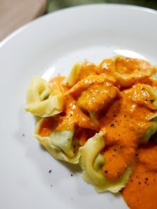 Närbild av tortellini med rostad paprikasås